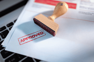Approved rubber stamp on trademark documents near laptop representing USPTO publication approval status in the federal trademark registration process