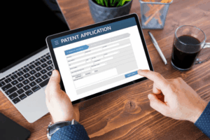 An inventor filling out an online patent application on a tablet, a crucial step that affects how long a patent lasts.
