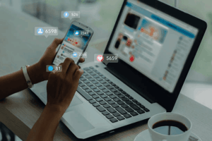 Business owner managing brand social media handles on phone and laptop to protect trademark rights online