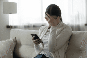 Concerned business owner holding a smartphone after receiving disappointing news about a trademark application or legal issue.