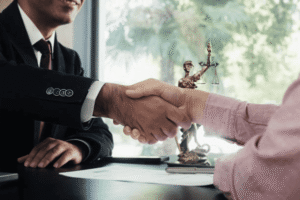 Trademark attorney and client handshaking after successfully negotiating a trademark coexistence agreement with Lady Justice statue in background
